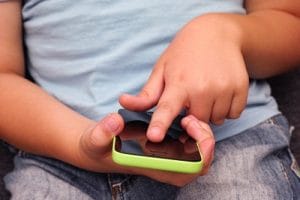 Empresa de telefonia móvel faz cobrança irregular a menor de idade e deve pagar danos morais 2 | Juristas Criança usando Celular Autor Professor25 _ Depositphotos_82221536_S