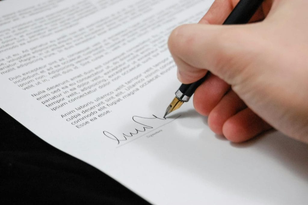 Modelo de contrato de aluguel de imóvel comercial para fins logísticos 2 | Juristas Person Signing in Documentation Paper