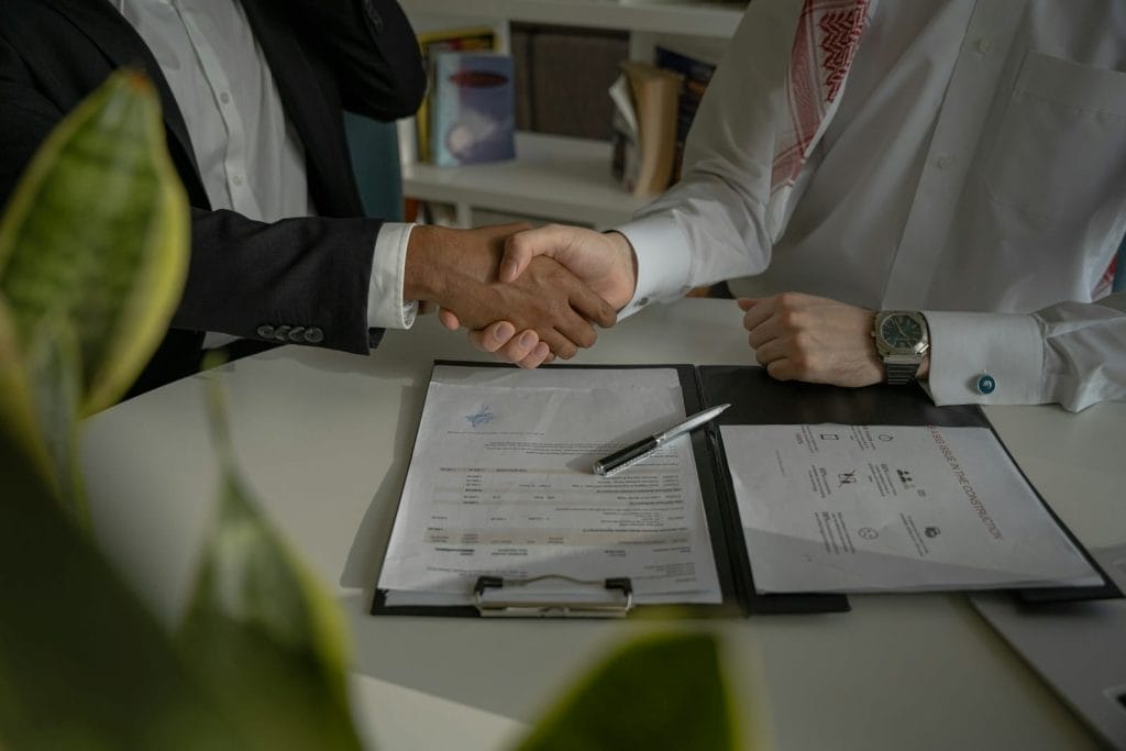Modelo de contrato para revisão de cláusulas contratuais por advogado 2 | Juristas two people shaking hands over a piece of paper
