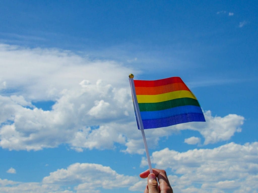 Homem trans será indenizado por não ter nome social reconhecido em registro bancário 1 | Juristas person holding flag of america under white clouds and blue sky during daytime