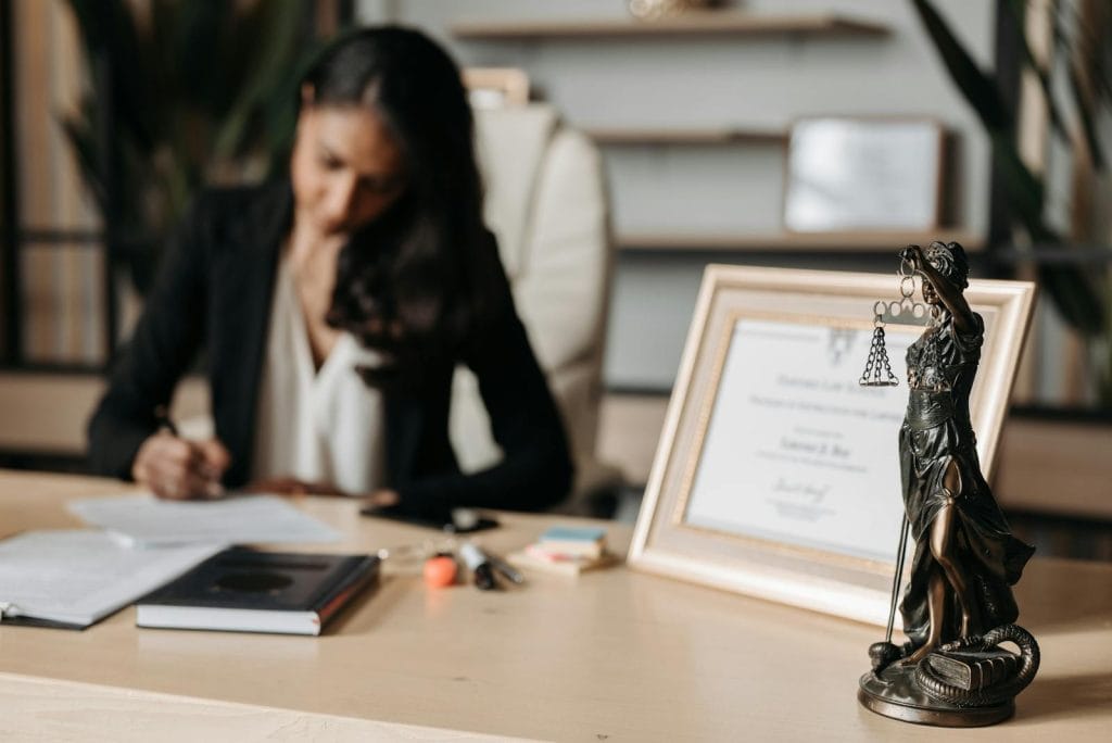 Modelo de Réplica à Contestação em Ação de Indenização por Danos Morais e Materiais - Carro Vendido sem Documentação - JEC 2 | Juristas Lady Justice Figurine on Wooden Table