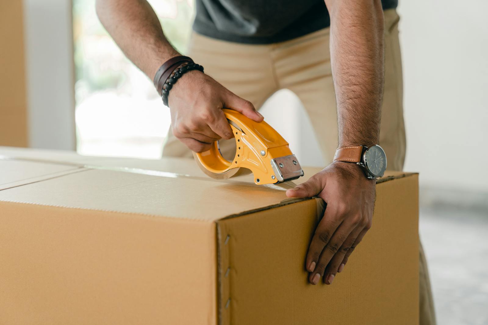 Modelo de petição de ação de reparação a título de danos morais e materiais por extravio de mercadoria pelos Correios 2 | Juristas Crop faceless young male with wristwatch using adhesive tape while preparing cardboard box for transportation