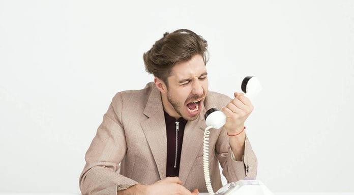 Man Wearing Brown Suit Jacket Mocking on White Telephone